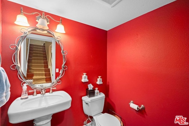 bathroom with sink, a textured ceiling, and toilet