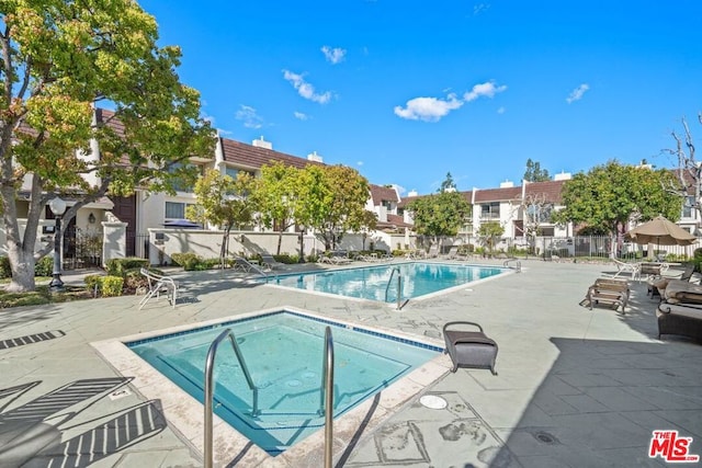 view of pool with a hot tub and a patio area