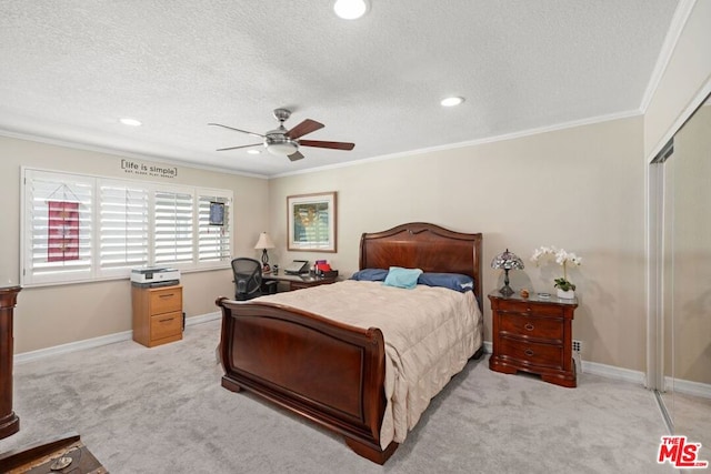 bedroom featuring light carpet, ornamental molding, a textured ceiling, ceiling fan, and a closet