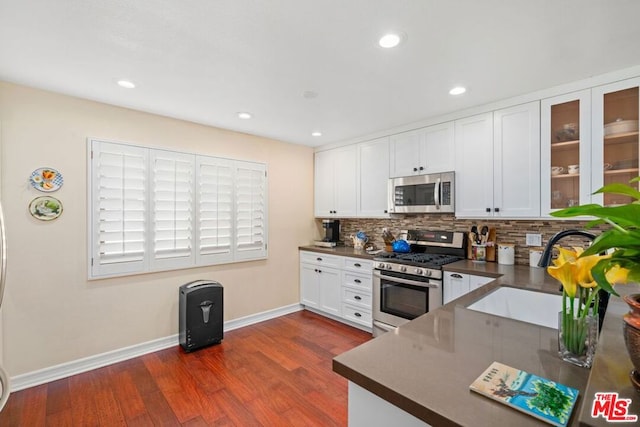 kitchen with dark wood-type flooring, white cabinets, sink, tasteful backsplash, and stainless steel appliances