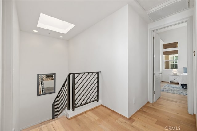 hall with hardwood / wood-style flooring and a skylight