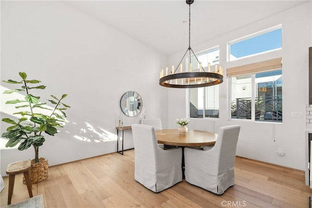 dining space with light hardwood / wood-style flooring, a chandelier, and a high ceiling