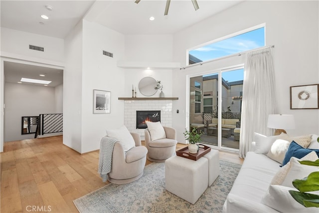 living room with light hardwood / wood-style flooring, a high ceiling, and a fireplace