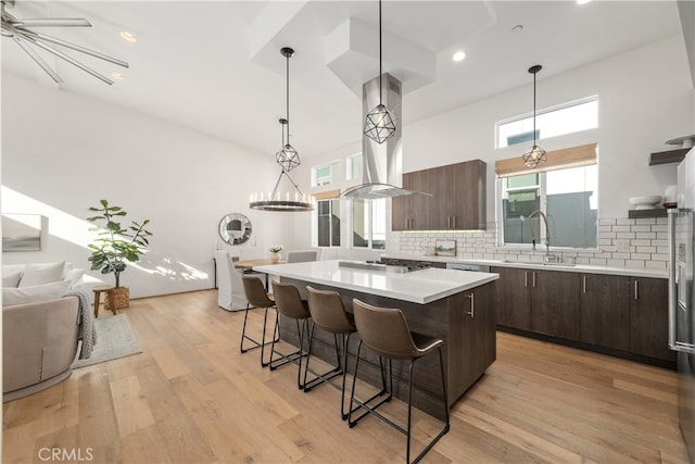 kitchen with island exhaust hood, a center island, dark brown cabinets, and sink