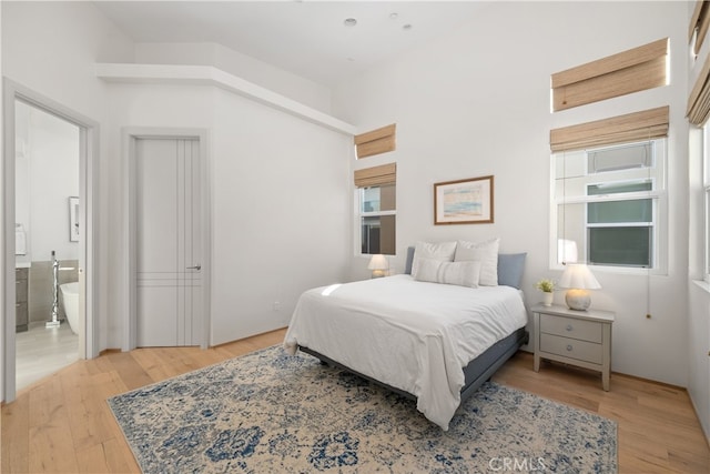 bedroom featuring light hardwood / wood-style floors, multiple windows, and ensuite bathroom