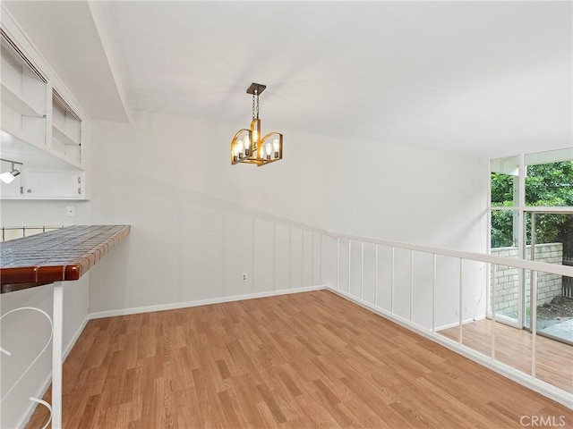 unfurnished dining area with light hardwood / wood-style flooring and a chandelier