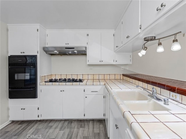 kitchen featuring tile countertops, white cabinetry, sink, and light hardwood / wood-style flooring