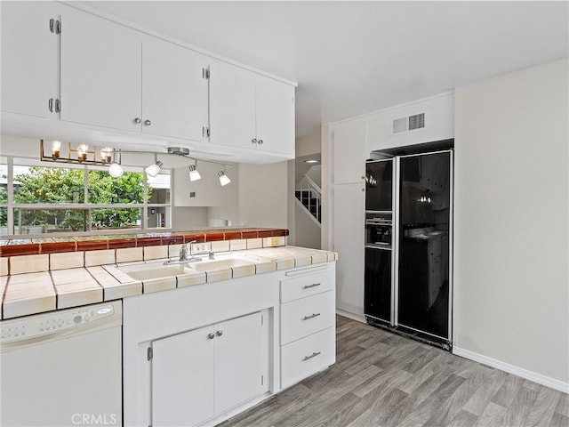 kitchen with dishwasher, white cabinets, sink, tile counters, and black fridge with ice dispenser