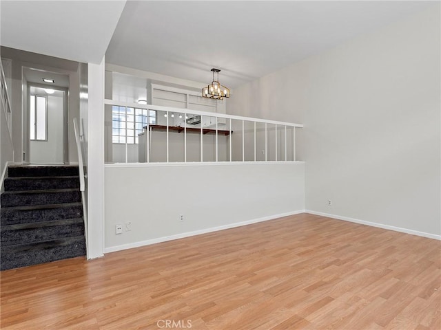 unfurnished living room featuring light wood-type flooring and an inviting chandelier