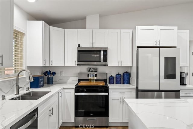 kitchen with white cabinetry, sink, appliances with stainless steel finishes, and vaulted ceiling