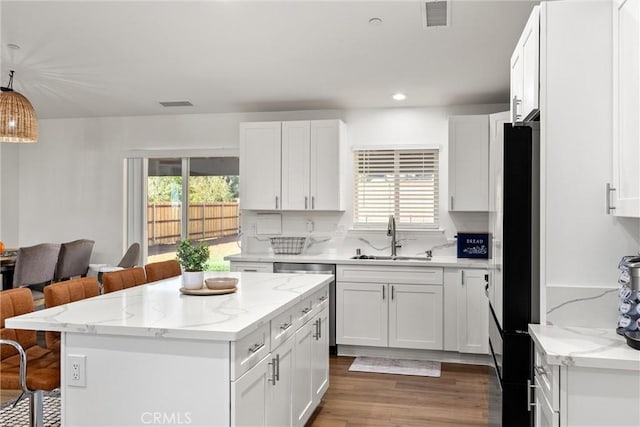 kitchen with pendant lighting, a healthy amount of sunlight, sink, and a breakfast bar area