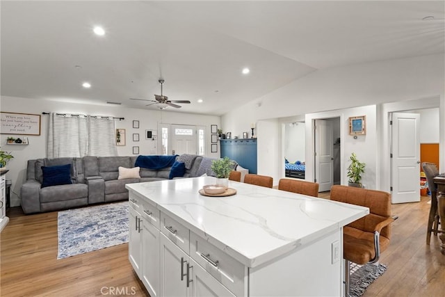 kitchen with white cabinetry, a breakfast bar, a kitchen island, and light wood-type flooring