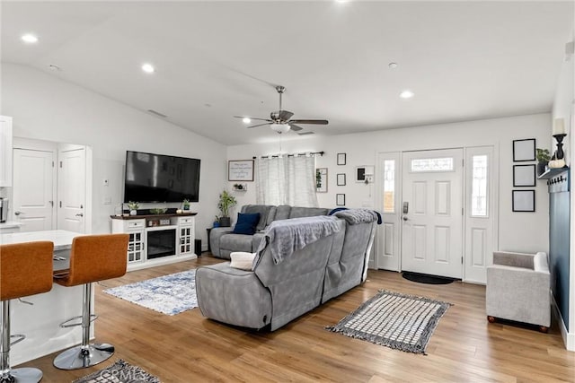 living room featuring light hardwood / wood-style floors, vaulted ceiling, and ceiling fan