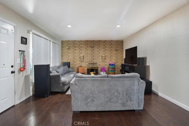 living room with dark wood-type flooring and a brick fireplace