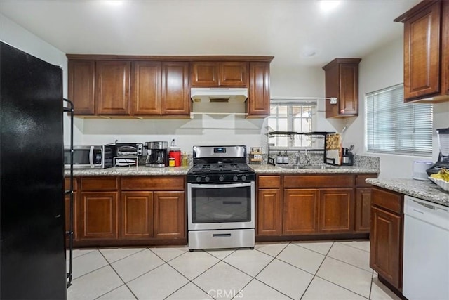 kitchen with light stone counters, appliances with stainless steel finishes, sink, and light tile patterned floors