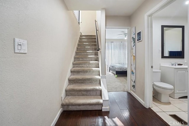 stairway featuring wood-type flooring, sink, and ceiling fan