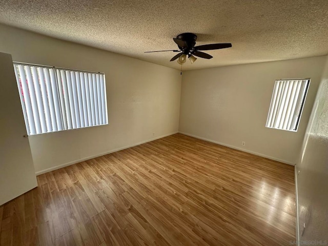 unfurnished room featuring ceiling fan, a wealth of natural light, and light wood-type flooring