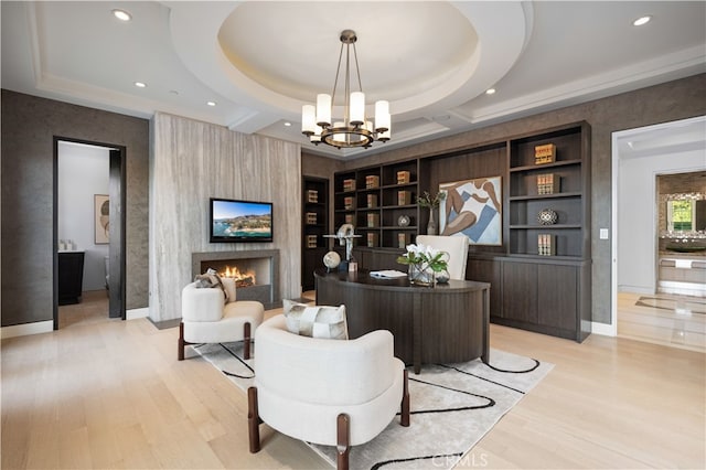 office space with coffered ceiling, a large fireplace, built in features, an inviting chandelier, and light hardwood / wood-style floors