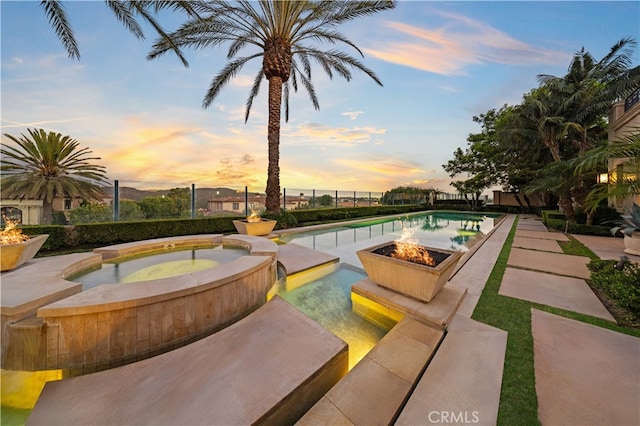 pool at dusk with an in ground hot tub