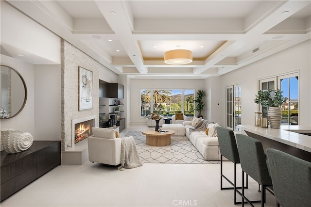 living room with beamed ceiling, coffered ceiling, and a large fireplace