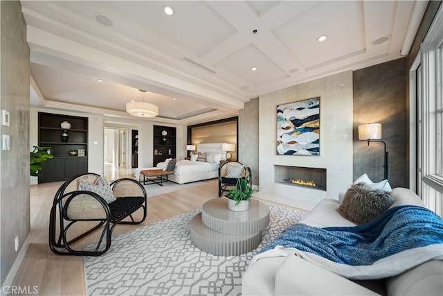 living room with beam ceiling, coffered ceiling, light wood-type flooring, and a fireplace