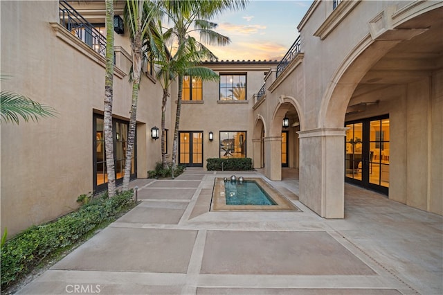 pool at dusk featuring a patio