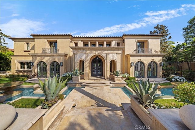 mediterranean / spanish-style house featuring a balcony, french doors, and a patio area