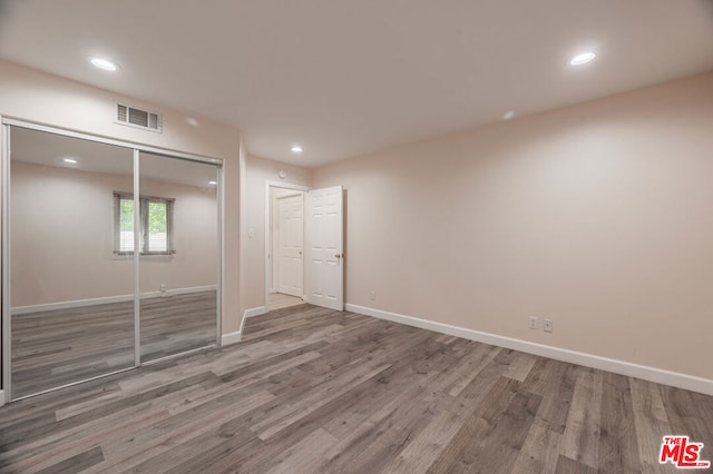 unfurnished bedroom featuring a closet and hardwood / wood-style floors