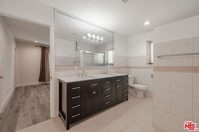 bathroom featuring vanity, toilet, wood-type flooring, and tile walls