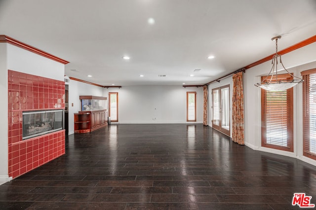 unfurnished living room with a tiled fireplace, dark wood-type flooring, and ornamental molding