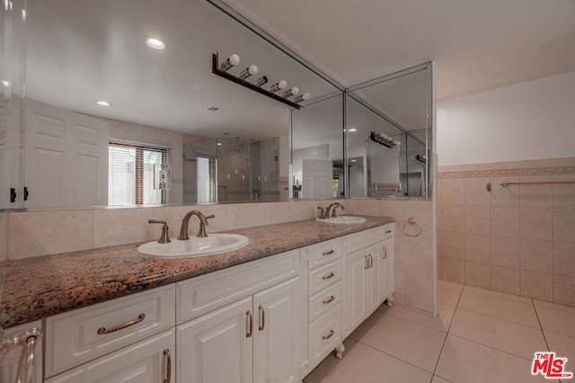 bathroom featuring walk in shower, vanity, tile patterned floors, and tile walls