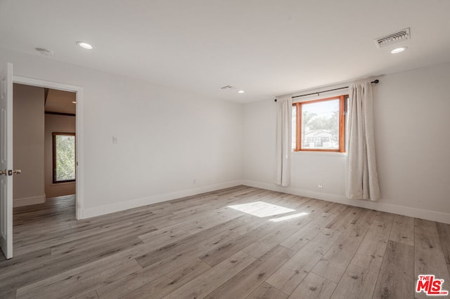 spare room featuring a healthy amount of sunlight and light hardwood / wood-style floors