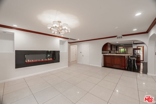 unfurnished living room featuring crown molding, light tile patterned floors, and an inviting chandelier