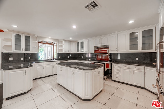 kitchen with a center island, white cabinets, light tile patterned floors, and sink