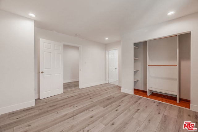 unfurnished bedroom featuring a spacious closet, light hardwood / wood-style flooring, and a closet