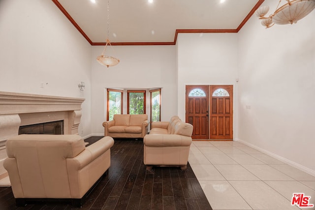 living room featuring a towering ceiling, ornamental molding, and hardwood / wood-style flooring