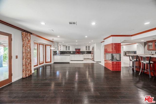 living room with a tile fireplace, dark wood-type flooring, and crown molding