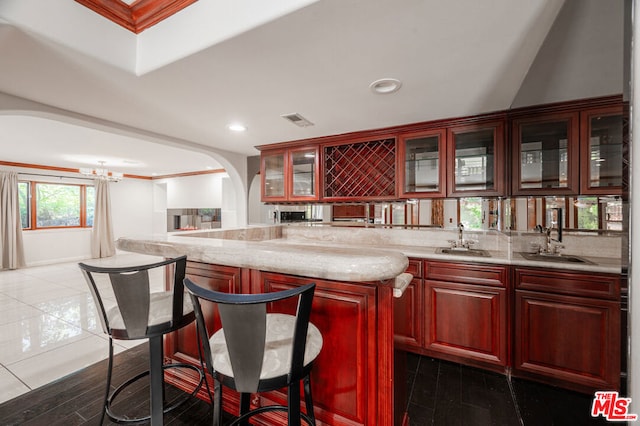 kitchen with dark tile patterned flooring, light stone counters, sink, and a chandelier