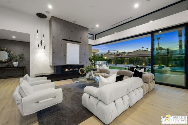 living room with light hardwood / wood-style floors, a large fireplace, and a high ceiling