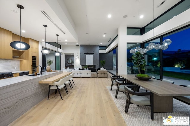 dining room featuring a towering ceiling, light hardwood / wood-style flooring, and sink