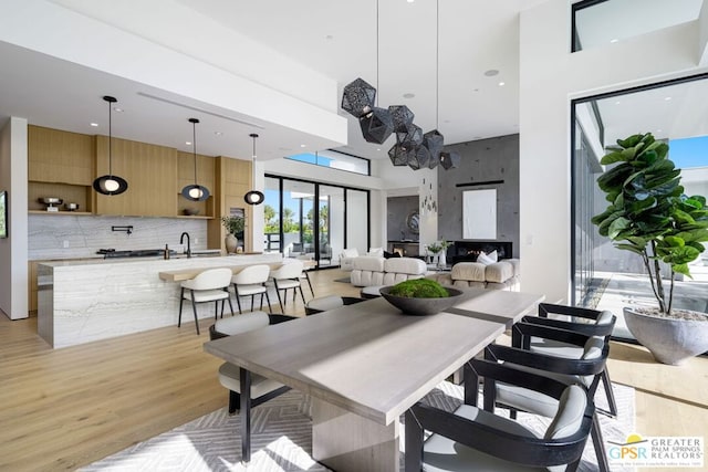 dining area featuring sink, light hardwood / wood-style flooring, and a high ceiling