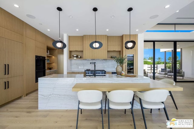 kitchen with tasteful backsplash, light hardwood / wood-style floors, stainless steel range, pendant lighting, and black double oven