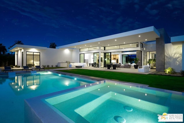 pool at night featuring a yard, an outdoor living space, and a patio area