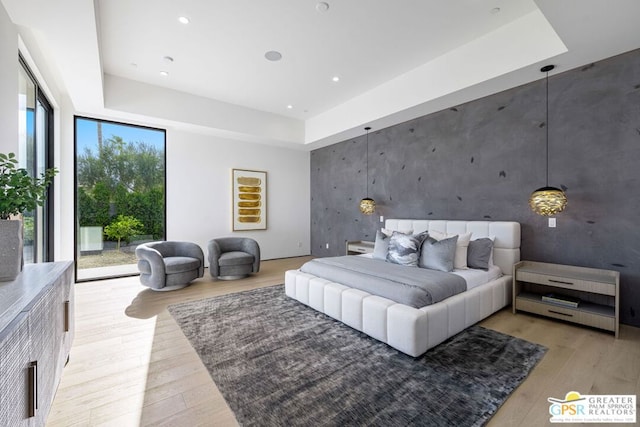 bedroom featuring light hardwood / wood-style floors, multiple windows, access to outside, and a raised ceiling