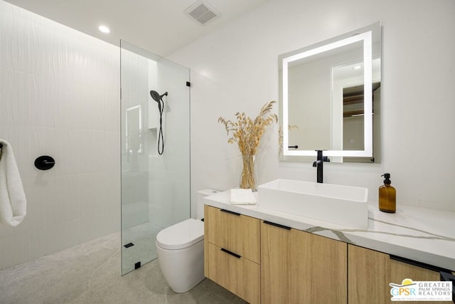 bathroom featuring vanity, toilet, and tiled shower