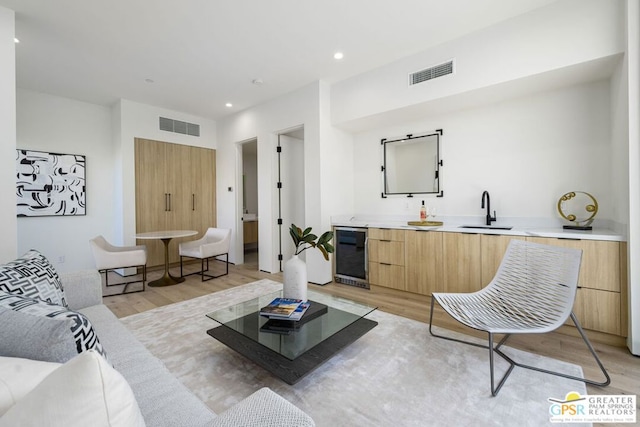 living room featuring wine cooler, light wood-type flooring, and indoor wet bar