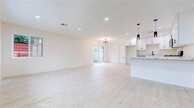 kitchen with pendant lighting, light countertops, visible vents, open floor plan, and white cabinetry