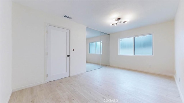 spare room with visible vents, light wood-style flooring, and baseboards