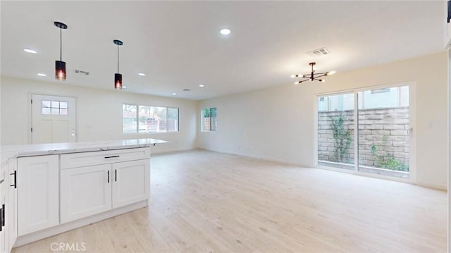 kitchen featuring visible vents, white cabinets, open floor plan, light wood-type flooring, and pendant lighting