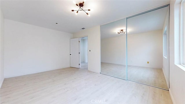 unfurnished bedroom with light wood finished floors, visible vents, and a closet